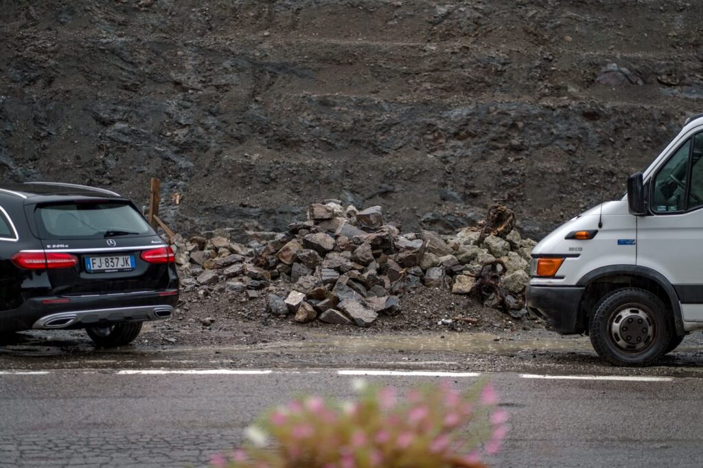 Eccolo, il Qualcosa: quel buco pietroso tra le auto, ai piedi di una diga costruita per arginare una frana.